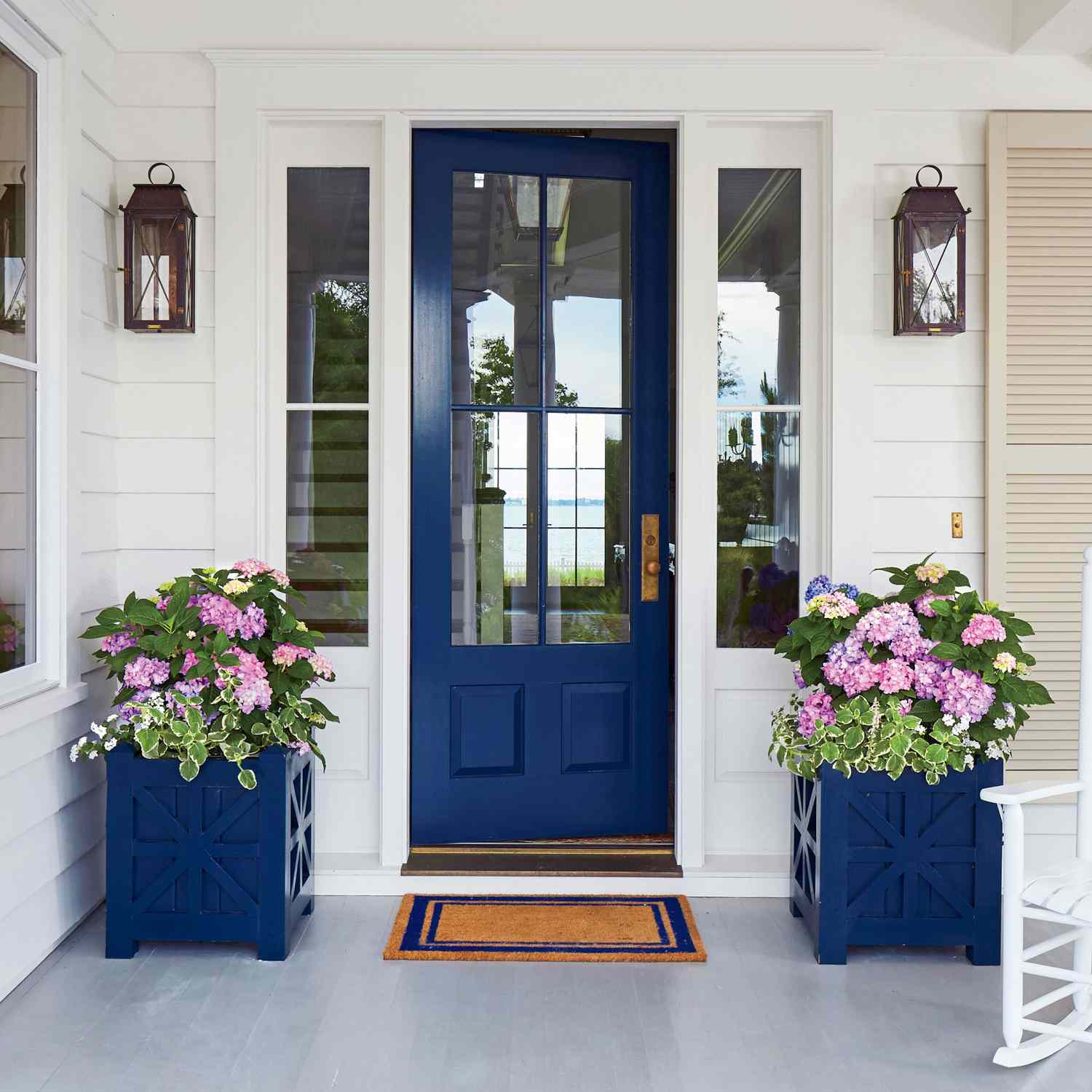 Blå inngangsdør med matchende beholdere med hortensia