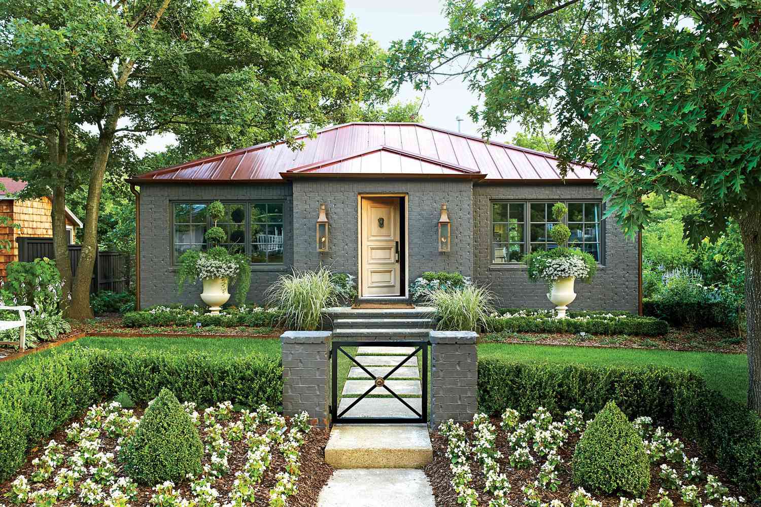 Gray House with White Annuals and Green Bushes