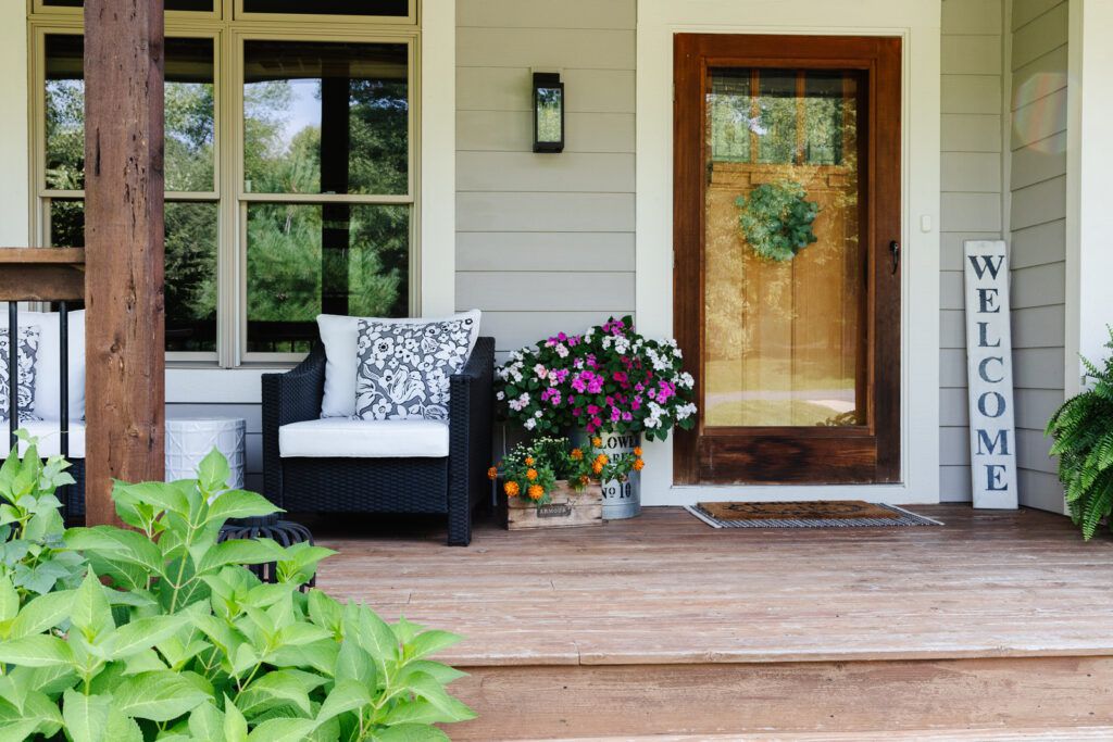 A porch with a comfortable chair and colorful flowers