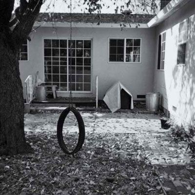 before photo of a backyard with a tire swing and a large tree