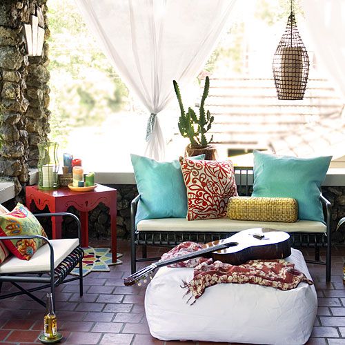 front porch with porch furniture (love seat and chairs with white cushions, colorful, red side table and a white bean bag in the middle with a guitar on top)