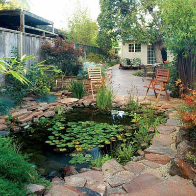 backyard lily pond surrounded by stones with a couple of lawn chairs positioned at the edge